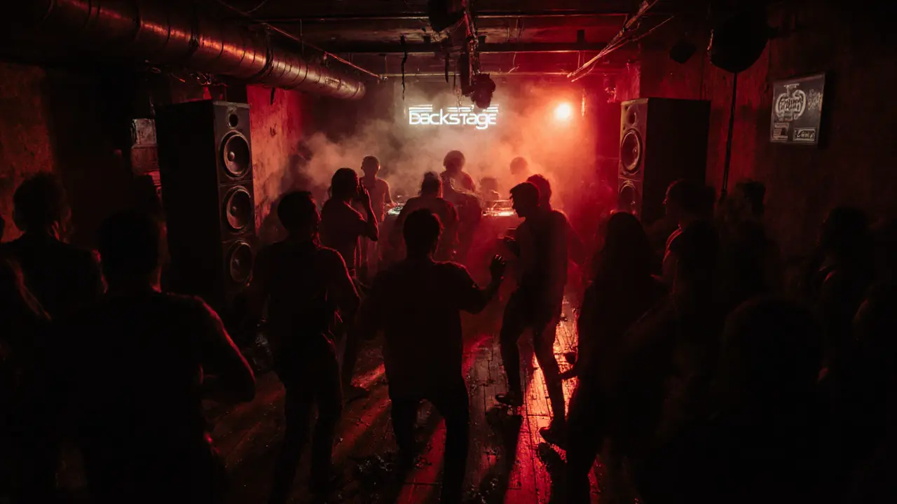 People dancing in a dim basement club with powerful speakers and red lighting.